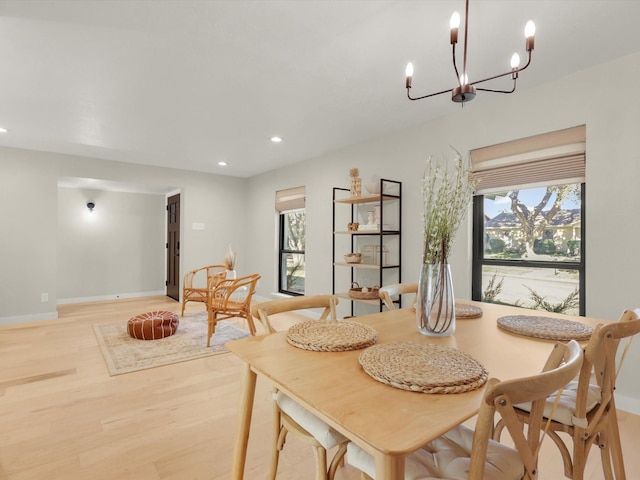 dining room featuring a healthy amount of sunlight, an inviting chandelier, and light wood-type flooring