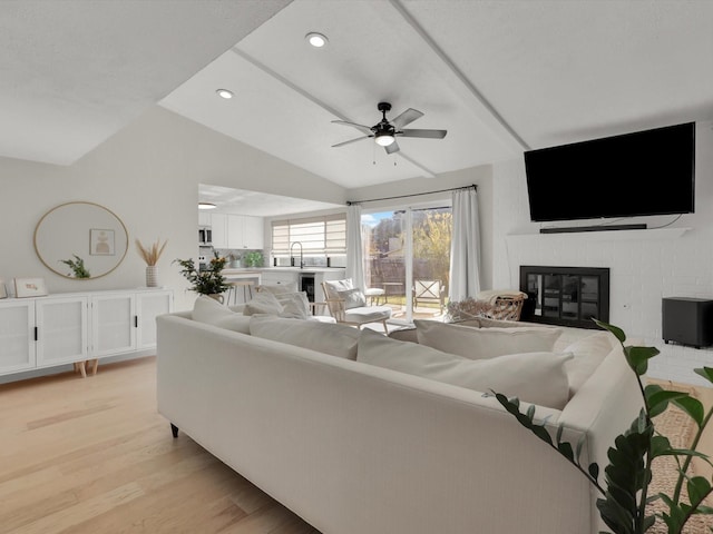 living room with a fireplace, light hardwood / wood-style floors, ceiling fan, and vaulted ceiling