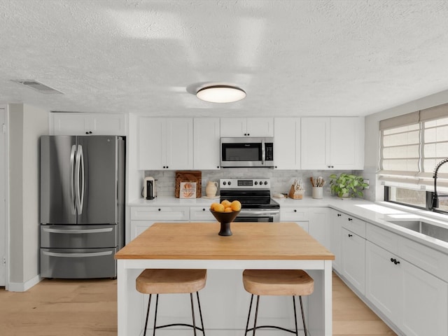 kitchen featuring stainless steel appliances, sink, a breakfast bar area, and white cabinets