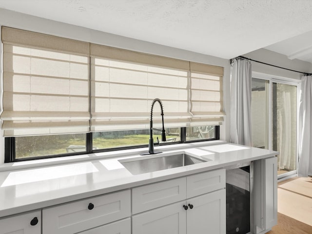 kitchen with sink, a textured ceiling, and white cabinets