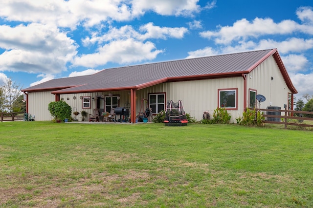 rear view of property featuring a lawn and cooling unit