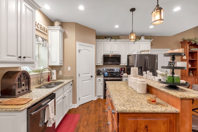 kitchen with stainless steel appliances, white cabinetry, a center island, and sink