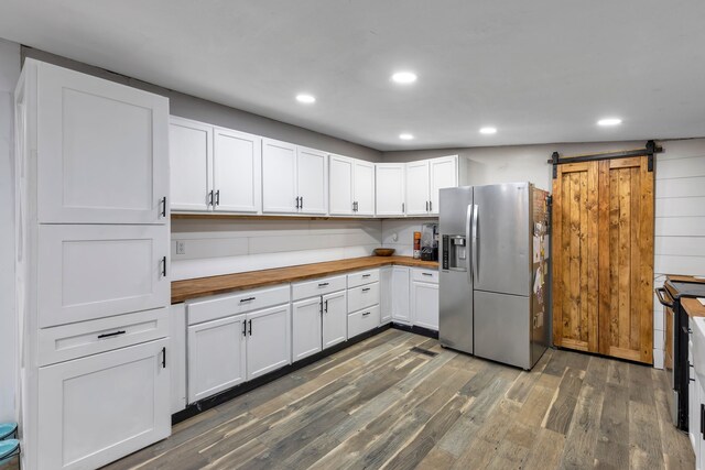 kitchen featuring stainless steel refrigerator with ice dispenser, a barn door, butcher block countertops, dark hardwood / wood-style flooring, and white cabinetry