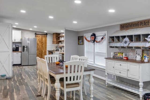 dining room featuring a barn door, dark hardwood / wood-style floors, and ornamental molding