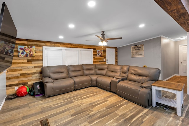 living room with ceiling fan, ornamental molding, wood-type flooring, and wooden walls