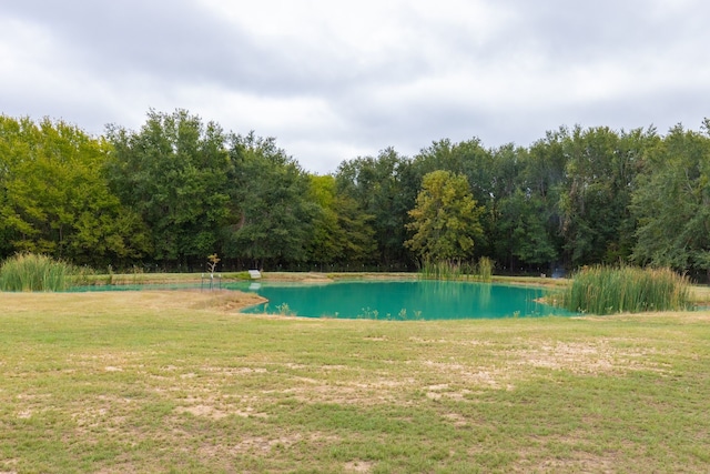 view of pool with a water view and a yard