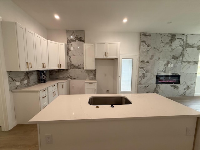 kitchen with light stone counters, light hardwood / wood-style flooring, white cabinets, and a kitchen island