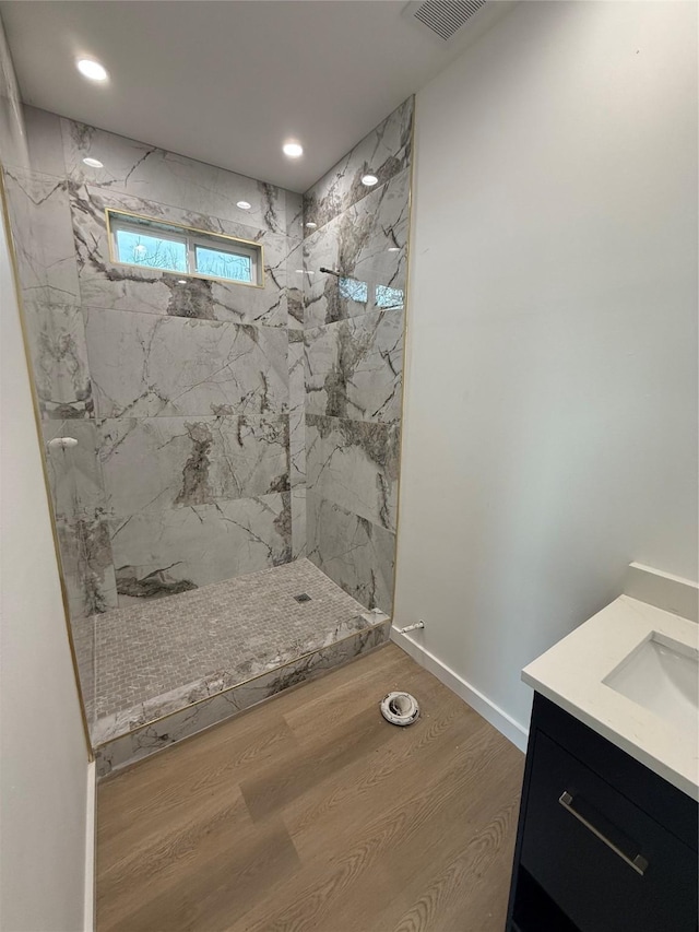 bathroom with vanity, wood-type flooring, and tiled shower