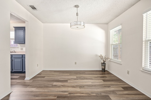 unfurnished dining area featuring sink, dark hardwood / wood-style flooring, and a textured ceiling