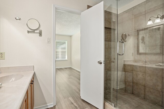 bathroom featuring vanity, wood-type flooring, a textured ceiling, and a shower with shower door