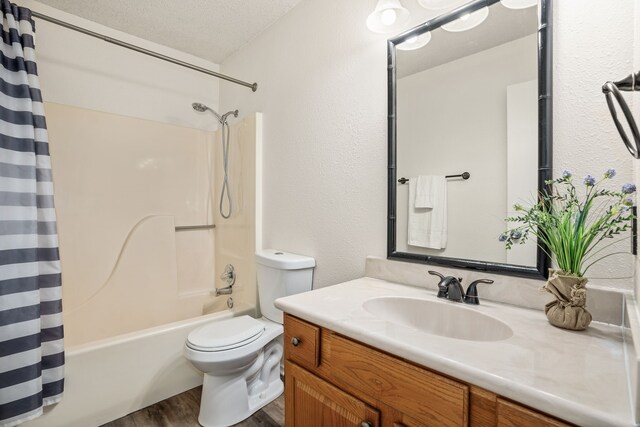 full bathroom with shower / bath combo, vanity, a textured ceiling, hardwood / wood-style floors, and toilet