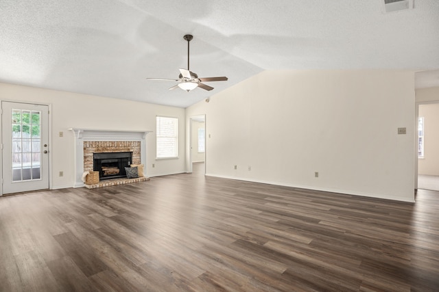 unfurnished living room with lofted ceiling, ceiling fan, dark hardwood / wood-style floors, and a brick fireplace