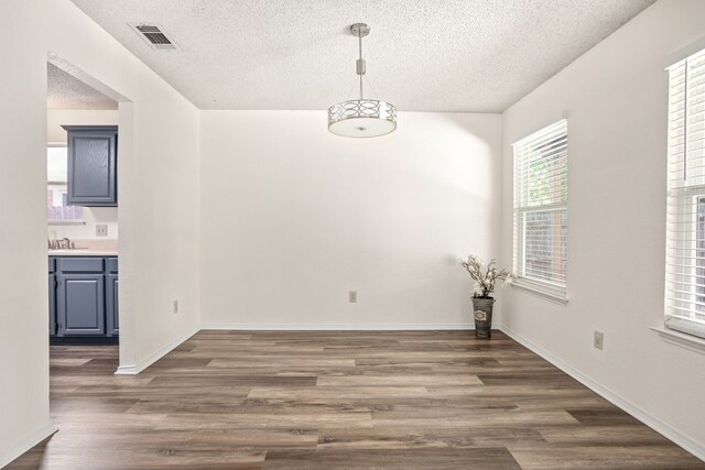 unfurnished living room featuring a textured ceiling, dark hardwood / wood-style flooring, a brick fireplace, and lofted ceiling