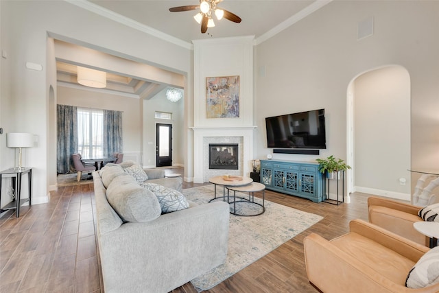 living room featuring ceiling fan, a high ceiling, and ornamental molding