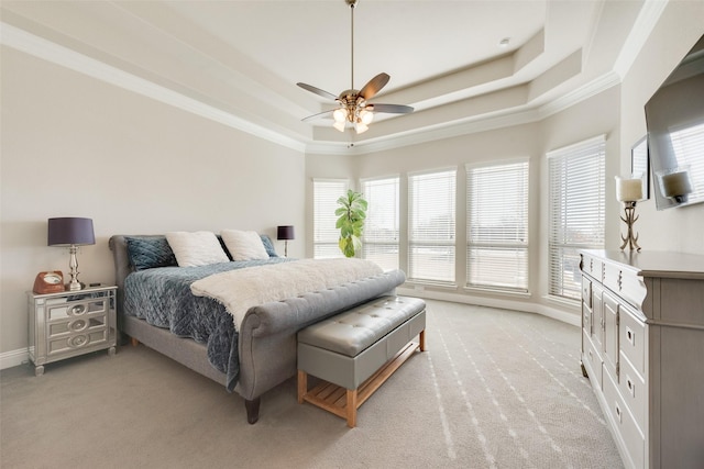 carpeted bedroom with a tray ceiling, multiple windows, ceiling fan, and crown molding