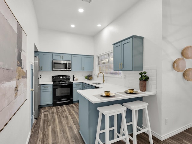 kitchen featuring sink, dark wood-type flooring, black electric range, kitchen peninsula, and decorative backsplash