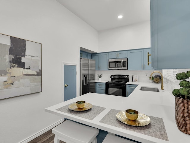 kitchen with kitchen peninsula, stainless steel appliances, blue cabinets, sink, and dark hardwood / wood-style floors