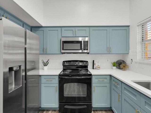 kitchen featuring decorative backsplash, wood-type flooring, blue cabinets, and stainless steel appliances