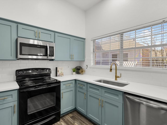 kitchen featuring appliances with stainless steel finishes, backsplash, dark wood-type flooring, and sink