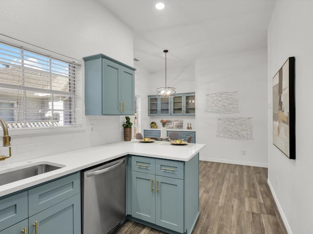 kitchen with dark wood-type flooring, sink, stainless steel dishwasher, decorative light fixtures, and kitchen peninsula