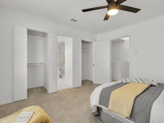 bedroom featuring light carpet, ensuite bathroom, ornamental molding, two closets, and ceiling fan