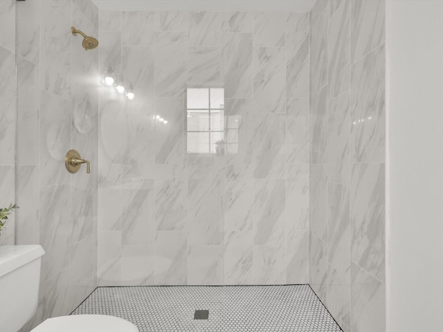 bathroom with a tile shower and toilet