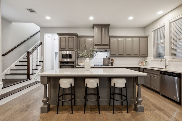 kitchen with sink, light hardwood / wood-style flooring, a breakfast bar area, appliances with stainless steel finishes, and a center island