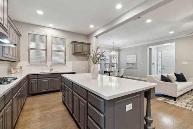 kitchen featuring gray cabinets, a kitchen island, tasteful backsplash, wood-type flooring, and sink