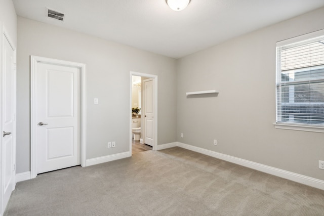 unfurnished bedroom with light carpet and ensuite bath