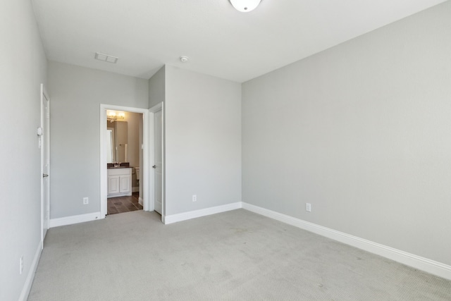 unfurnished bedroom with ensuite bath and light carpet