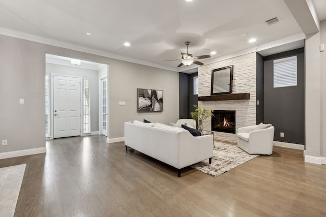 living room featuring ceiling fan, ornamental molding, a fireplace, and hardwood / wood-style floors