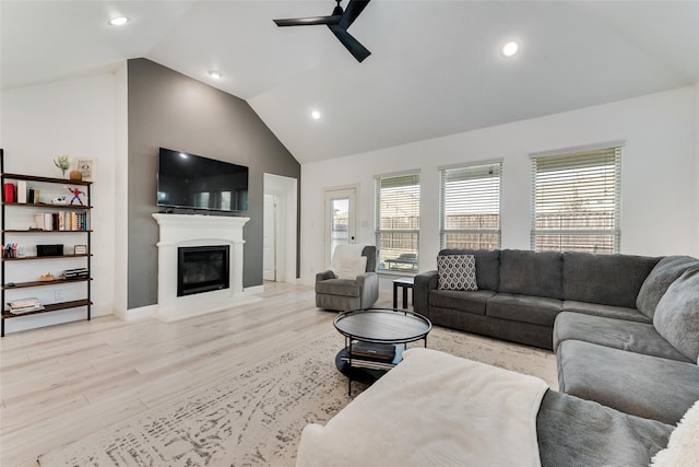 living room featuring ceiling fan, high vaulted ceiling, and light hardwood / wood-style flooring