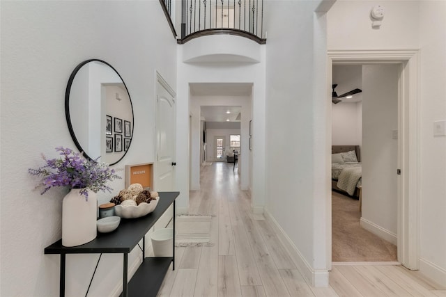 hallway featuring a towering ceiling and light hardwood / wood-style flooring