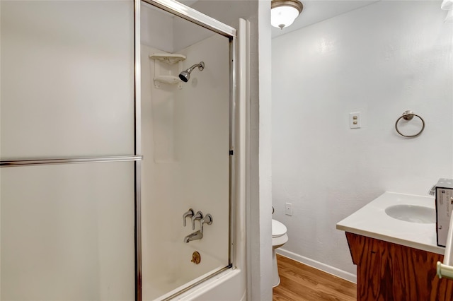 full bathroom with vanity, combined bath / shower with glass door, hardwood / wood-style floors, and toilet