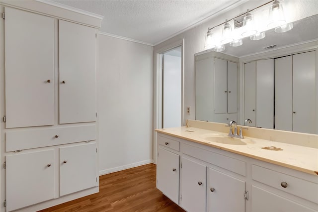 bathroom with crown molding, vanity, hardwood / wood-style flooring, and a textured ceiling