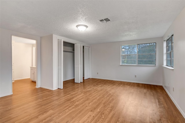 unfurnished bedroom with light hardwood / wood-style floors and a textured ceiling