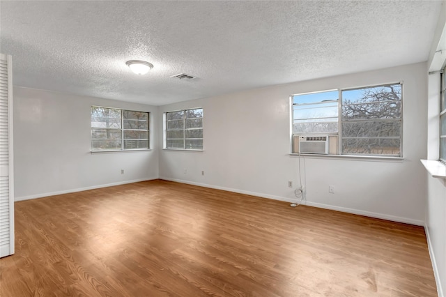 unfurnished room with cooling unit, wood-type flooring, and a textured ceiling