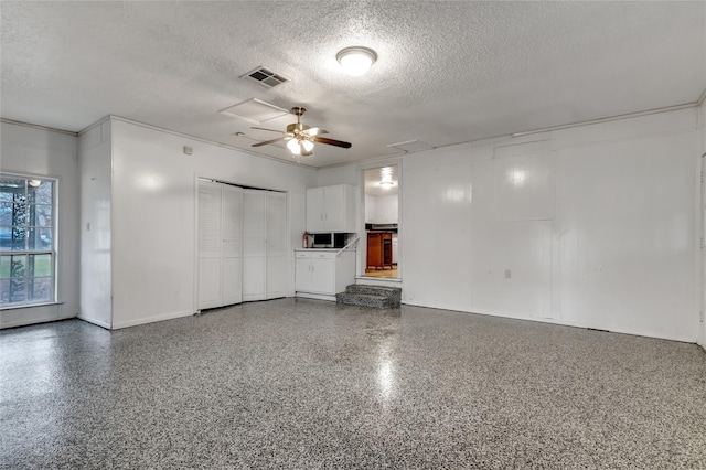 unfurnished living room with ceiling fan and a textured ceiling