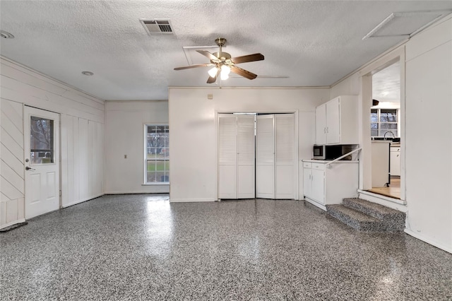 unfurnished living room featuring ceiling fan and a textured ceiling