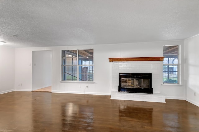 unfurnished living room with dark hardwood / wood-style flooring, a textured ceiling, and a fireplace