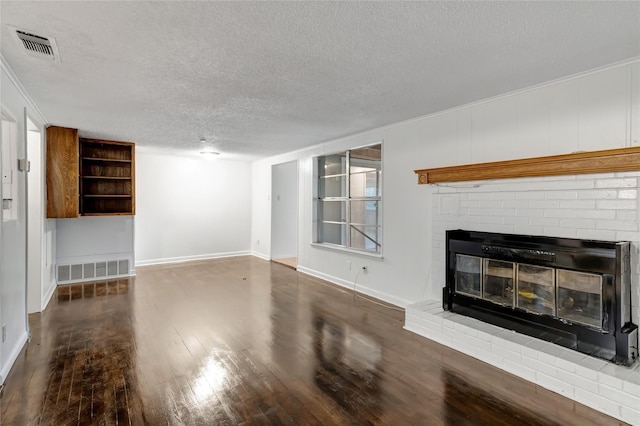 unfurnished living room with a brick fireplace, dark wood-type flooring, and a textured ceiling