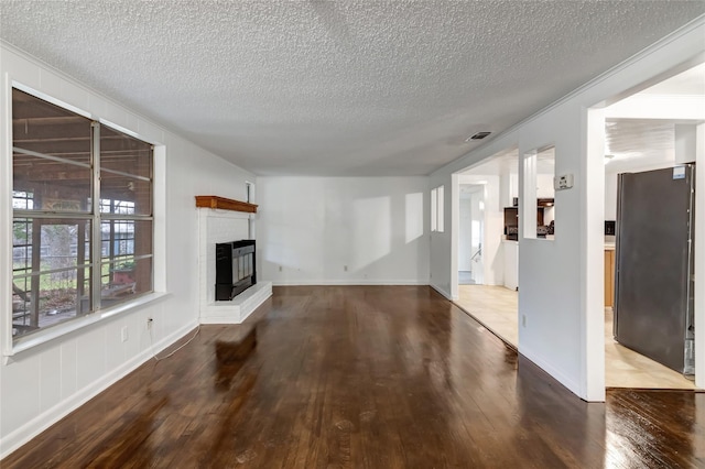 unfurnished living room with a textured ceiling, a fireplace, and wood-type flooring