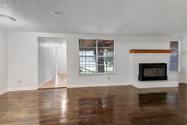 unfurnished living room with a brick fireplace, dark hardwood / wood-style floors, and a textured ceiling