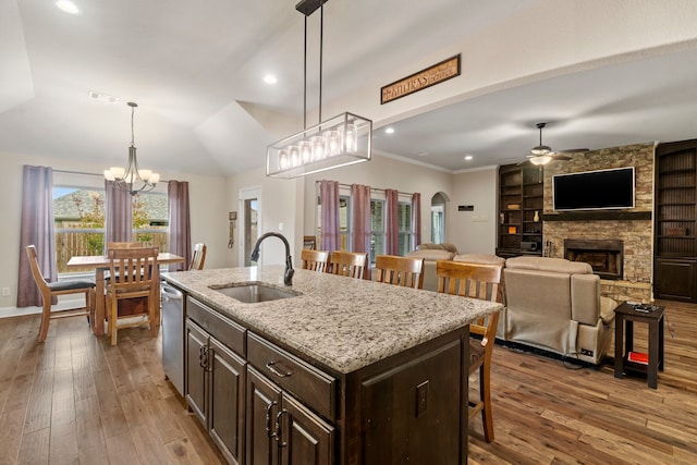 kitchen with a breakfast bar area, decorative light fixtures, dark brown cabinets, a center island with sink, and dishwasher