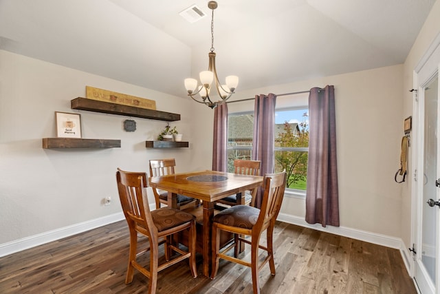 dining space featuring lofted ceiling, hardwood / wood-style flooring, and an inviting chandelier