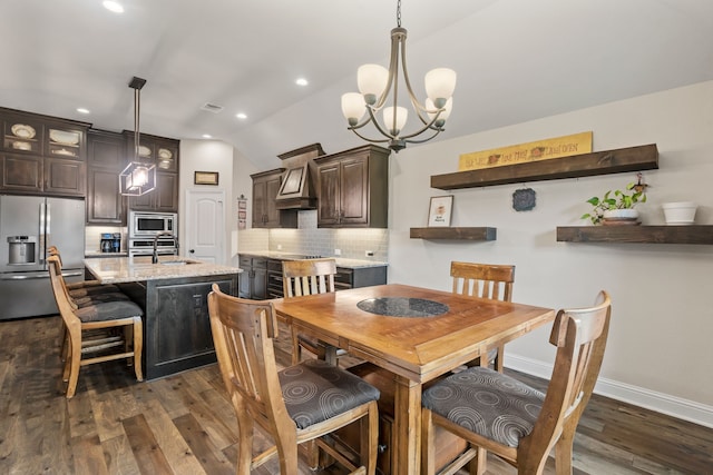 dining space with sink, dark hardwood / wood-style floors, vaulted ceiling, and a notable chandelier