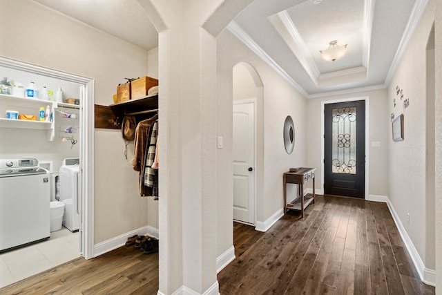 entrance foyer featuring a raised ceiling, crown molding, dark hardwood / wood-style floors, and independent washer and dryer