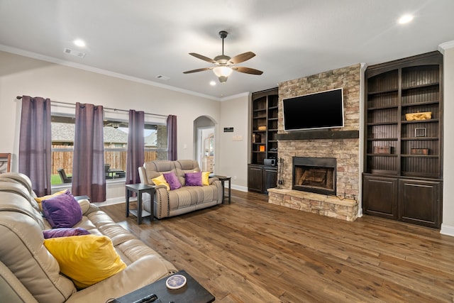 living room featuring crown molding, a stone fireplace, ceiling fan, and hardwood / wood-style flooring