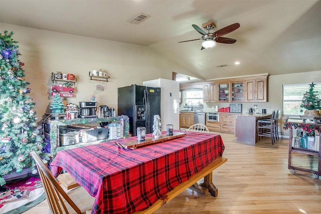 dining room featuring a wealth of natural light, sink, light hardwood / wood-style floors, and lofted ceiling