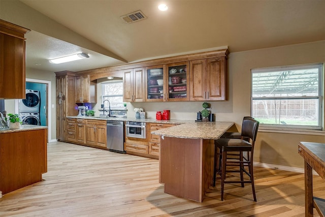 kitchen featuring sink, a breakfast bar, dishwasher, kitchen peninsula, and stacked washer / drying machine